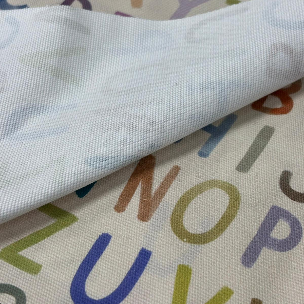 Close-up of fabric with colorful letters on a multicolored alphabet background
